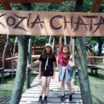 Dwie dziewczyny stojące pod napisem Kozia CHata