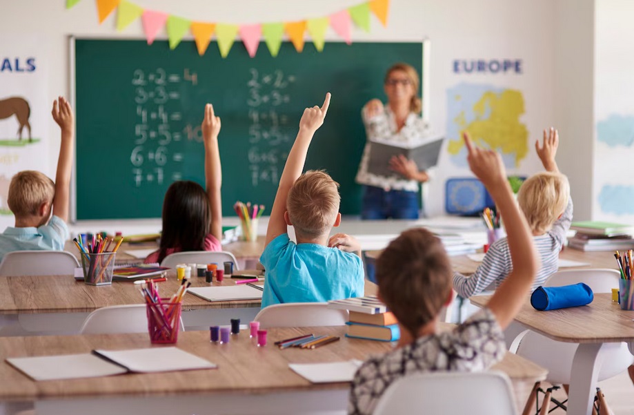 zdjęcie dzieci zgłaszających się do odpowiedzi w klasie w szkole